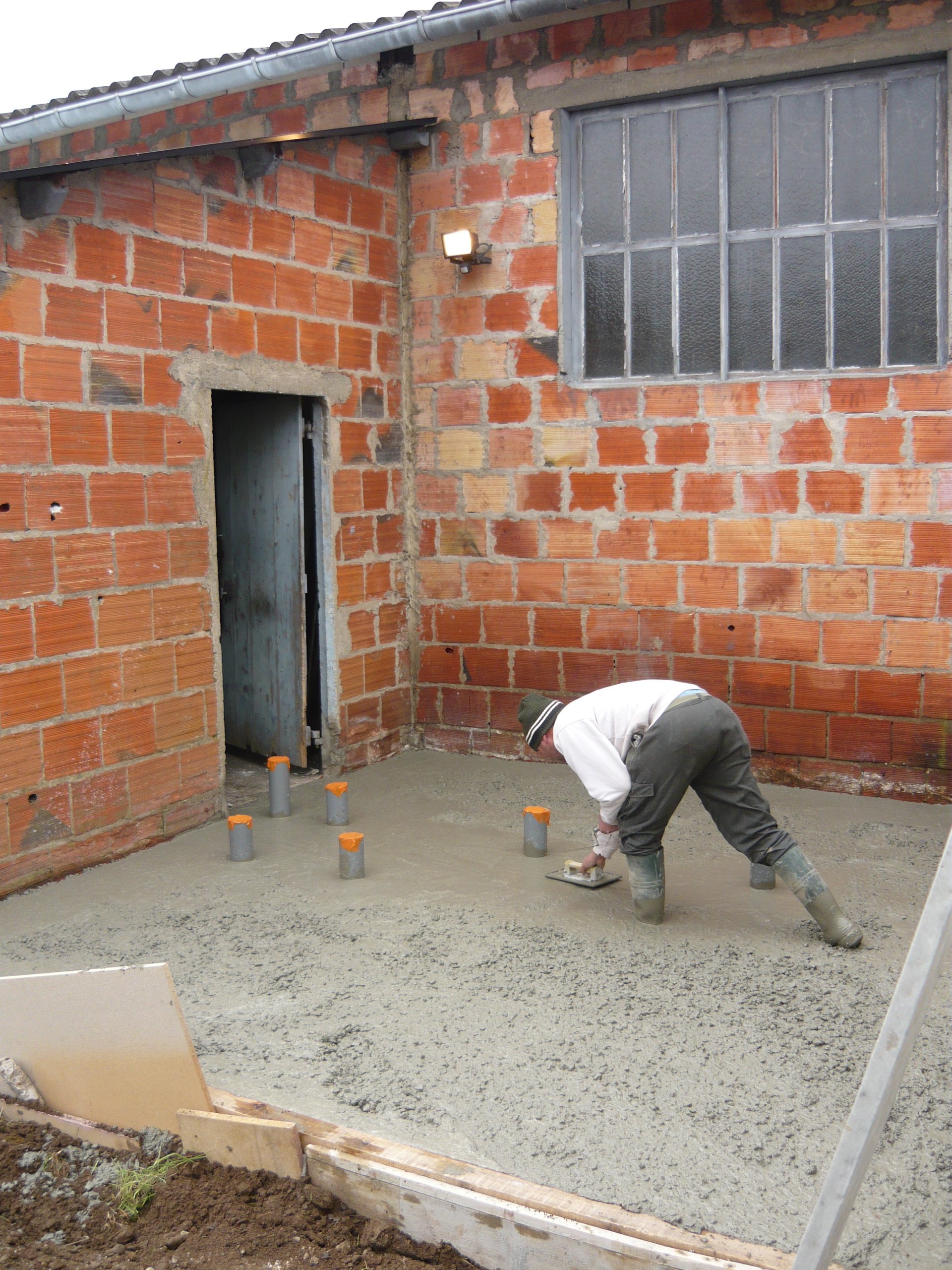 Coulage de dalle béton en cours, talochage à la règle